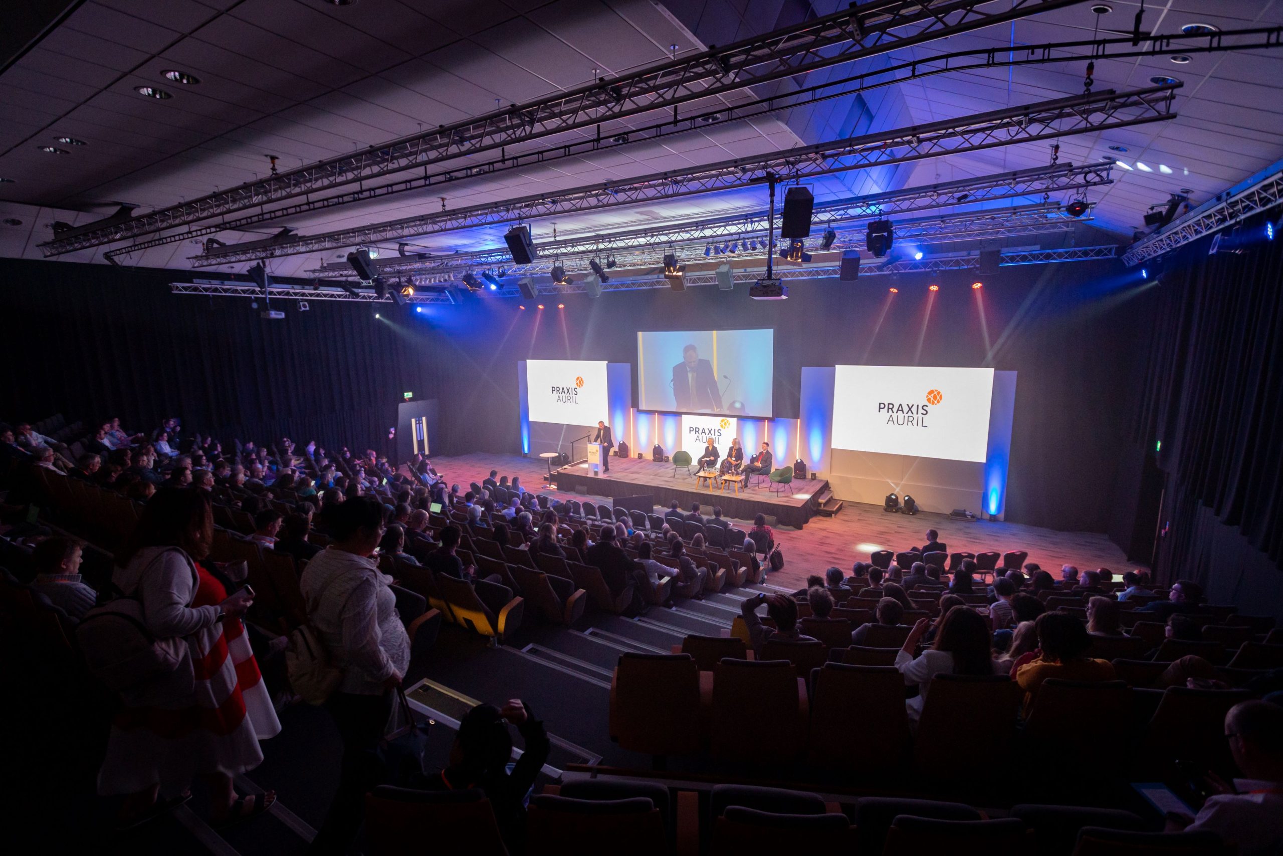 PraxisAuril Annual Conference delegates in auditorium.