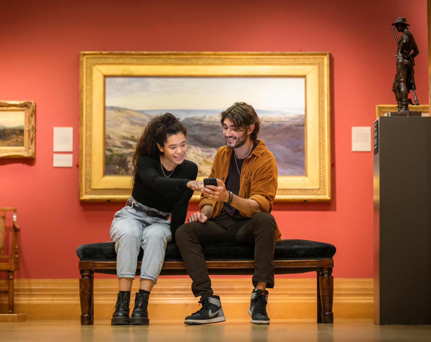 Two people in an art gallery looking at a smart phone.