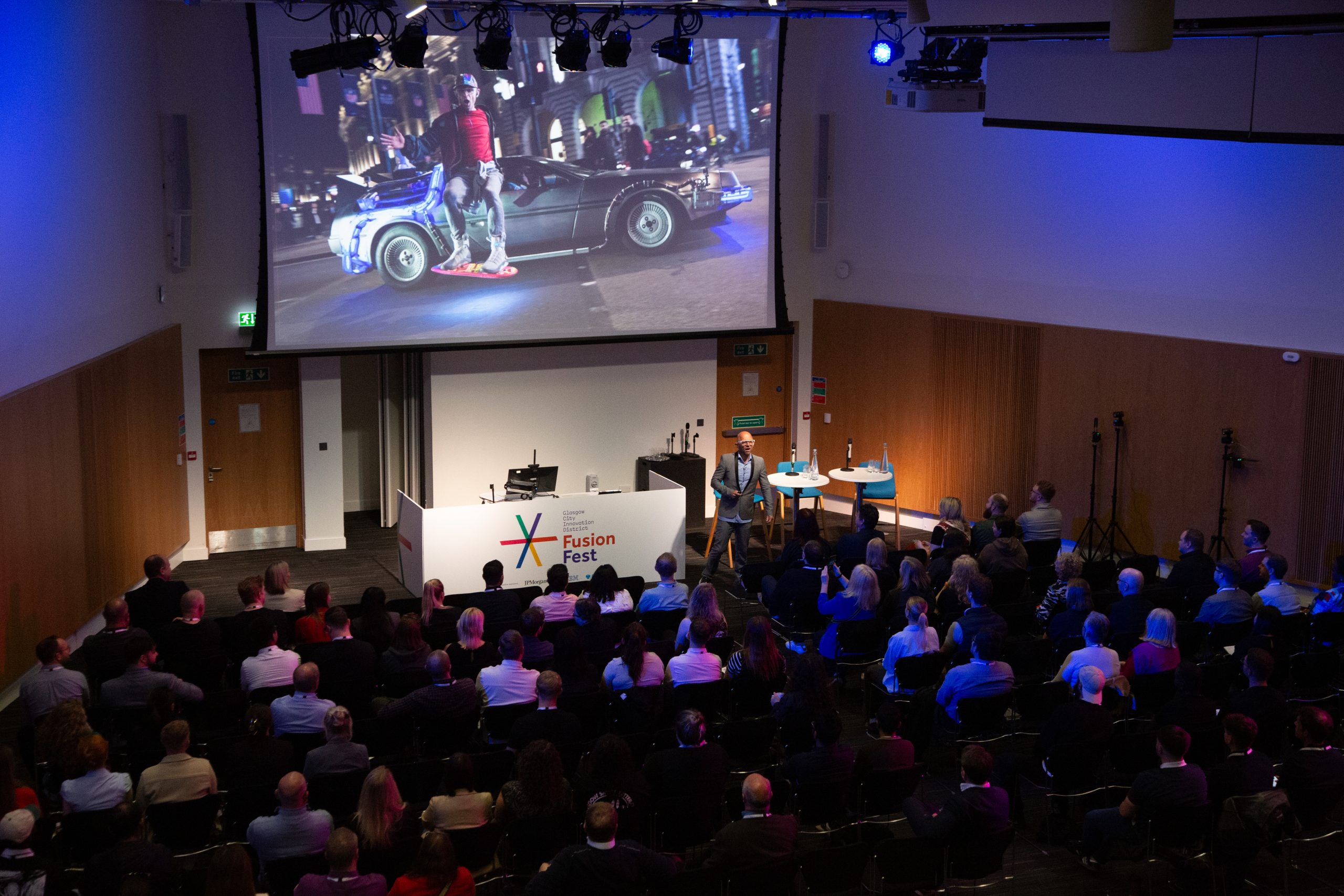 Delegates at Fusion Fest conference looking at a screen showing a man leaning against a car