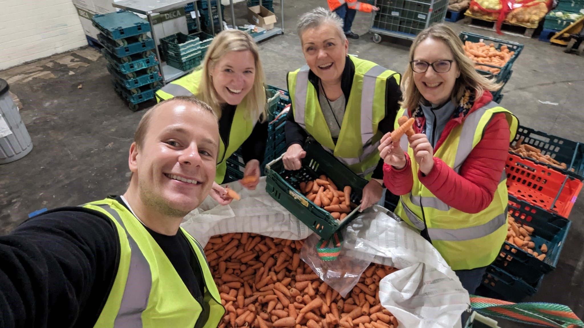 Four people in hi-vis jackets and a large bag of carrots volunteering